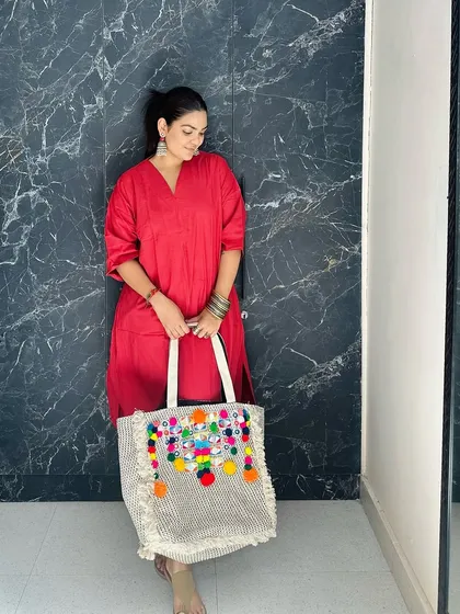This pose shows the tote from a different angle, highlighting the textured fabric and the craftsmanship of the handcrafted embellishments.
