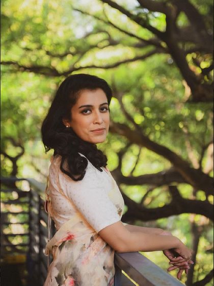 A lovely outdoor portrait in a floral sari. Her expression is warm and inviting, and the natural setting is beautiful.