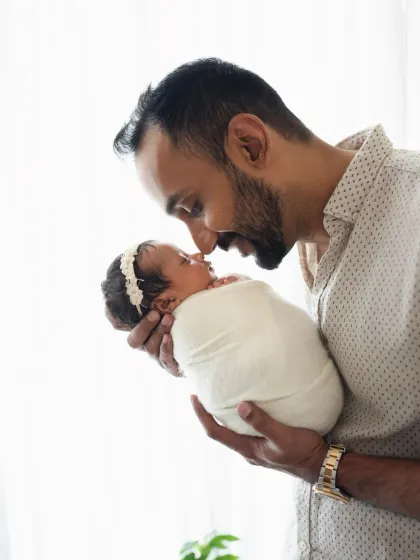 A father shares a sweet nose-to-nose moment with his swaddled newborn. This intimate portrait is a beautiful way to capture the father-baby bond.