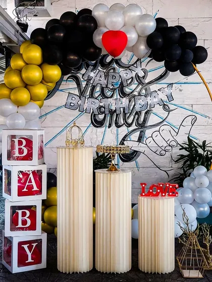 We combined a balloon arch with a cool, custom graffiti art backdrop for an urban and edgy vibe. This unique setup uses black, white, and gold balloons, along with classic pedestals and 'BABY' blocks, to create a one-of-a-kind party look.