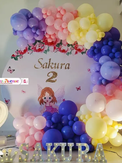 A closer look at the Sakura party backdrop, featuring a fairy cutout and the child's name in glittery gold.
