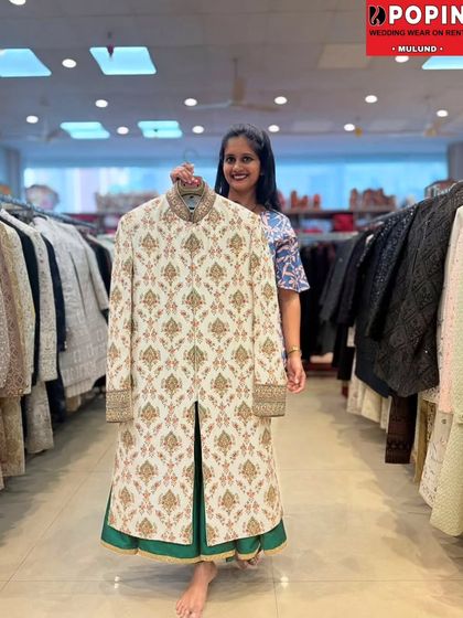 Here is a beautiful ivory sherwani with detailed block-print style embroidery, paired with a contrasting green inner kurta. It’s a sophisticated option for a groom looking for traditional elegance.