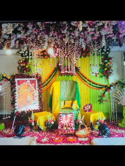 Another angle of the yellow and green themed Guruji decoration, showing the full stage layout. The design includes floral arches and a basket of fresh flowers as an offering.