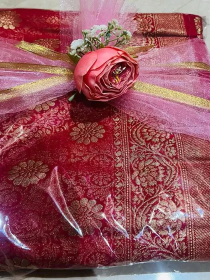 I love creating a soft and dreamy look for your gifts. This classic red and gold saree is wrapped in delicate pink tulle and tied with a matching flower, giving it a romantic feel that’s perfect for an engagement or wedding gift.