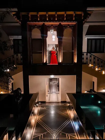 A dramatic, architectural bridal portrait. The bride in her red gown stands out against the heritage building at night, creating a powerful and cinematic image.