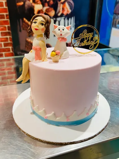 A sweet pink cake featuring a girl figurine and her cat, inspired by The Aristocats.