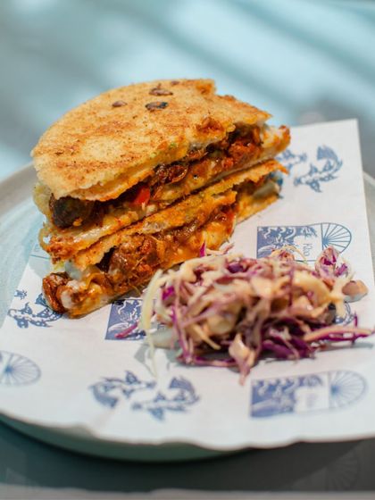 A smashed poee sandwich with a side of slaw, served on custom-printed paper during our pop-up with Klaa Kitchen. It’s the small details that make these events special.