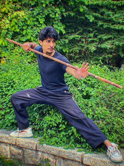 A dynamic pose with the Bo Staff, demonstrating the focus and form required for weapons training.