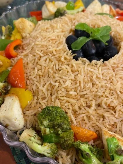 This is our three-bean Mexican rice, served with a side of grilled vegetables. The dish is garnished with olives and fresh basil, offering a hearty and healthy vegetarian meal option.