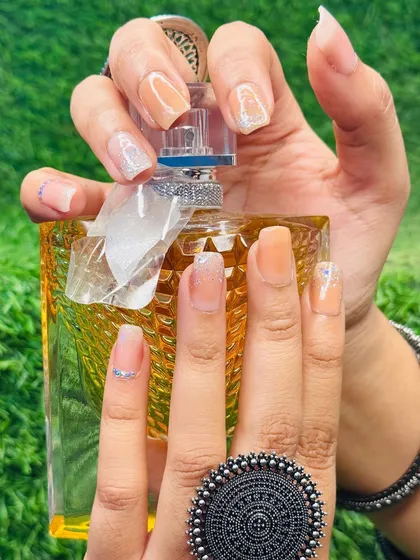 This elegant manicure features long, square-shaped nails with a nude ombre effect and subtle silver glitter accents, perfectly complementing the client's accessories.