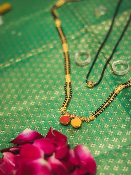 The sacred Mangalsutra and wedding rings, beautifully arranged on a traditional green silk cloth.