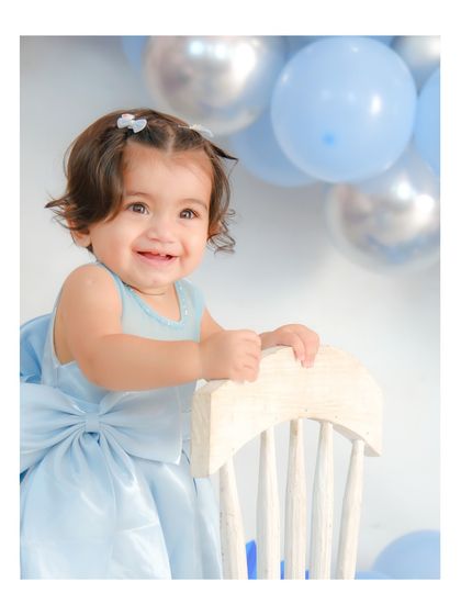 A happy smile from the birthday girl. Using a small chair as a prop helps babies who are just learning to stand, giving them support and confidence.