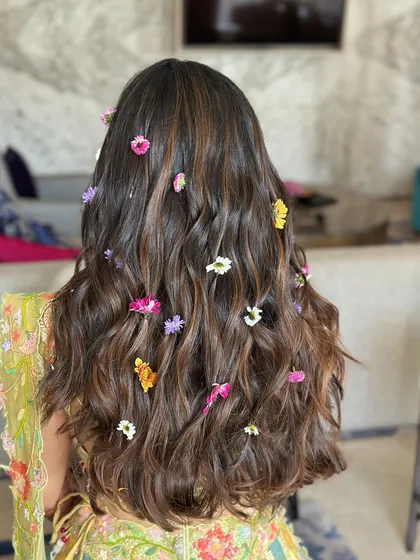 Open hair with a floral flair. For this mehendi look, I created soft waves and scattered colorful fresh flowers throughout the hair.