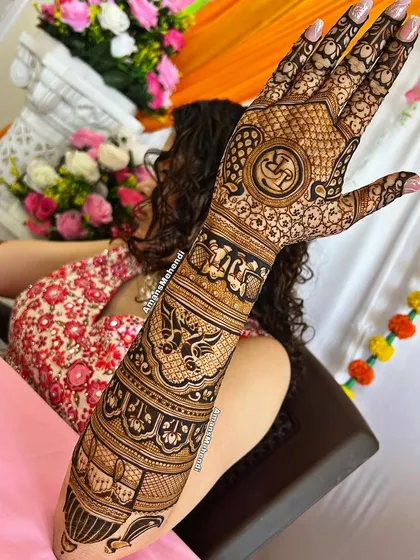 A beautiful bridal design featuring a sacred 'Om' symbol, surrounded by intricate patterns of elephants and birds, covering the entire back of the hand and arm.