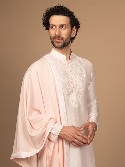 This powder pink kurta, paired with a matching stole, is a charming and elegant outfit. The white embroidery adds a touch of delicate contrast, making it perfect for any traditional event.
