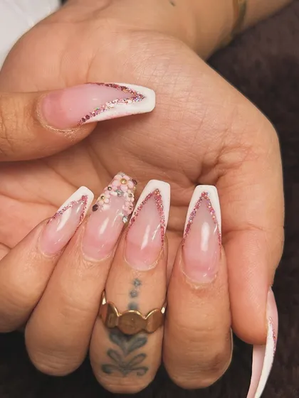 A dramatic V-cut French manicure. The long coffin nails feature a sharp white tip outlined with sparkling pink glitter.