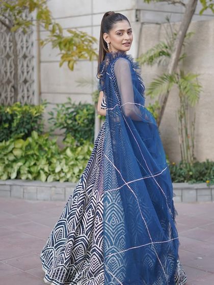 The back view of the navy and white lehenga, showing the delicate, ruffled dupatta and the continuation of the bold geometric pattern.