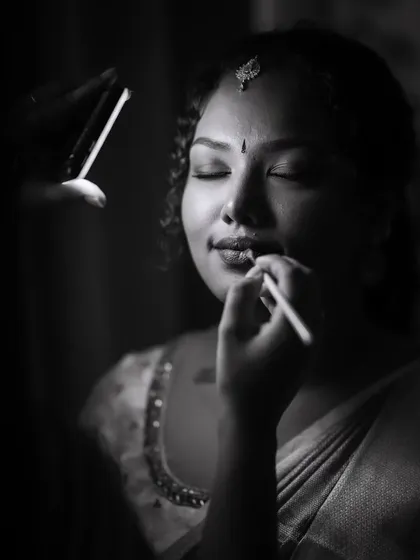 A black and white shot of me applying lipstick on a model, capturing the artistry and focus involved in my work.