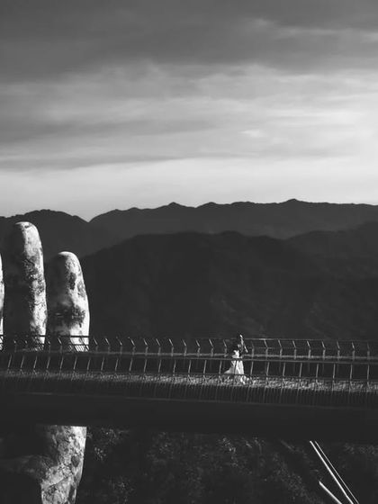 A dramatic black and white wide shot of the Golden Bridge, with the couple appearing small against the vast landscape. This artistic photo emphasizes the scale and grandeur of their destination shoot.