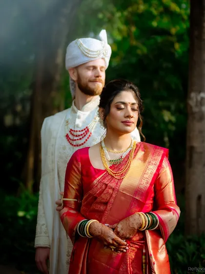 A stunning portrait of the couple. The bride's red saree and soft makeup create a beautiful contrast with the natural green background.