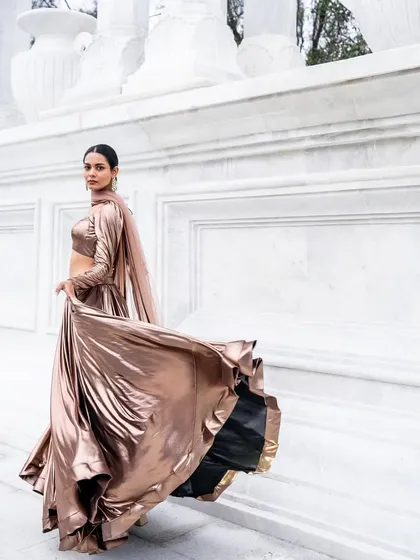 The metallic trend is here to stay, and this bronze lehenga is a showstopper. The liquid-like fabric has an incredible sheen and moves beautifully, with a full flare that gives it a luxurious feel. It's a contemporary look that is guaranteed to turn heads.