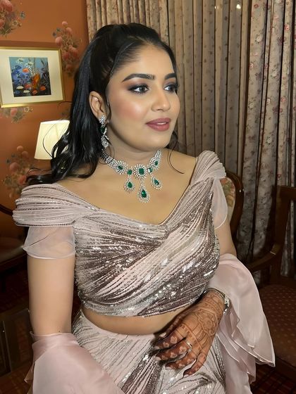 A close-up portrait showing the details of the eye makeup and the beautiful emerald jewelry.