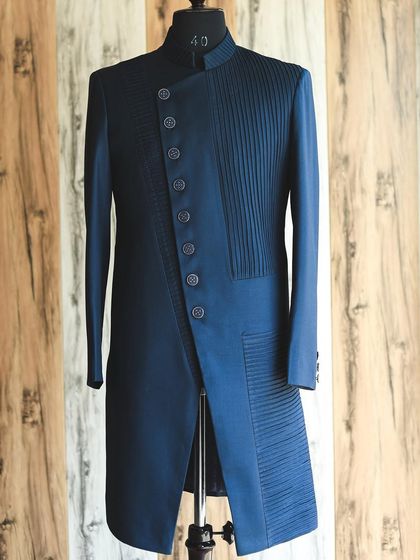 The full view of the navy blue pleated Indo-Western jacket. Its unique, angular design and sharp tailoring offer a sophisticated and fashion-forward alternative to traditional occasion wear.