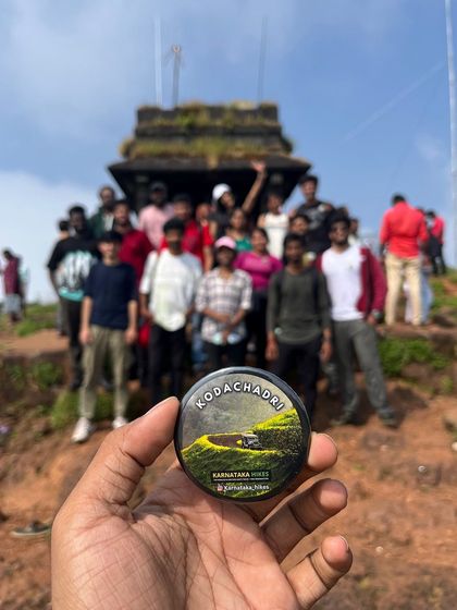 Our Kodachadri badge held up in front of the Sarvajna Peetha at the summit.