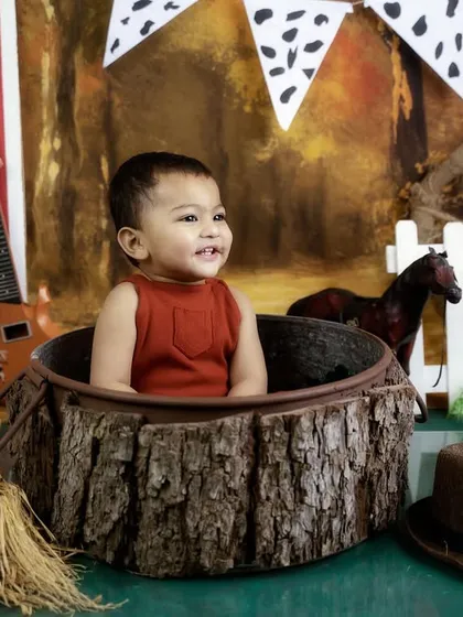 A happy smile from inside a rustic log prop. I use a variety of props to keep babies engaged and get those great shots.