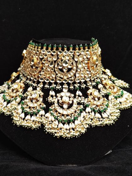 A stunning pearl and Kundan choker with green accents, available for rent.