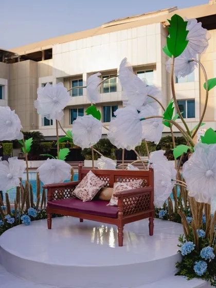 Another view of the whimsical photo booth, featuring a charming wooden bench surrounded by the oversized paper flowers.