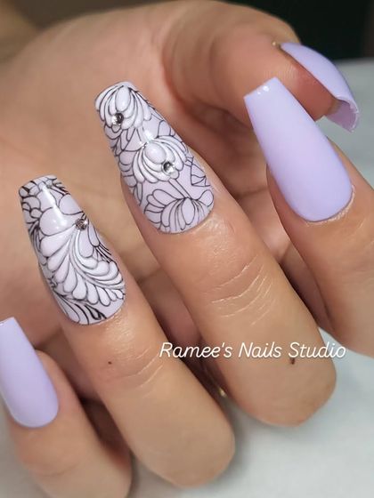 A beautiful lavender set with two accent nails featuring intricate, hand-drawn floral line art. The single rhinestone adds a perfect touch of sparkle.
