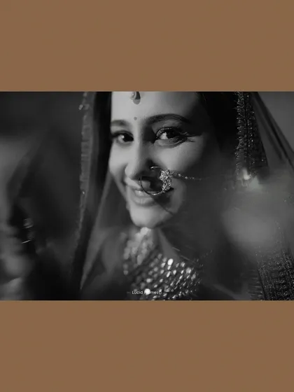A soft, dreamy black and white portrait of the bride, her smile peeking through a veil.