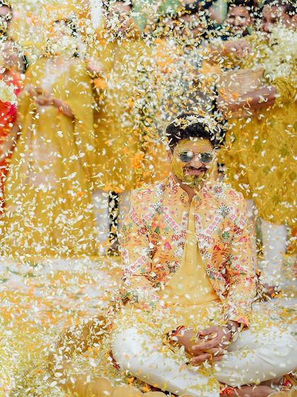 An explosion of petals! This shot perfectly captures the peak of the fun and madness during the groom's Haldi ceremony.