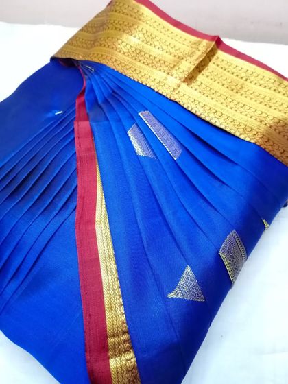 A royal blue saree with a red and gold border. The pleats are done to perfection, making it ready for a quick and elegant drape.
