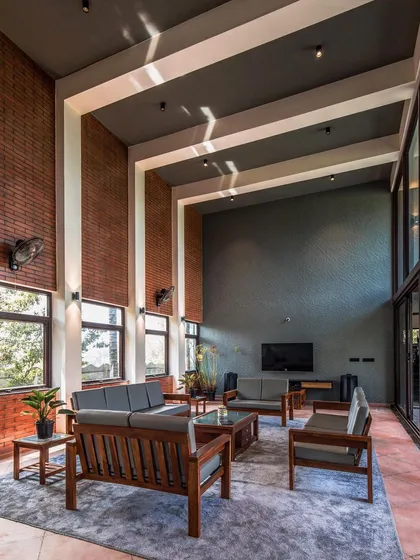 The living area of 'The Grey Grotto' showcases our contemporary style with its double-height ceiling, exposed brick walls, and textured grey surfaces. The material palette is chosen to create a space that feels both expansive and earthy.