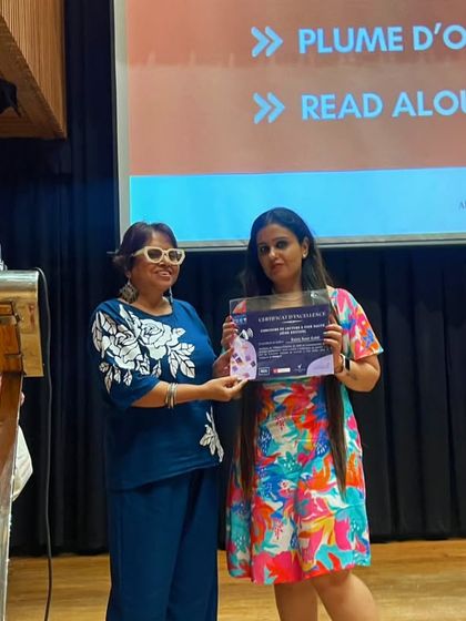 A student receives her award certificate on stage during our Bastille Day celebrations. We publicly recognize and honour the winners of various competitions like Défi Inter-Alliances and Read Aloud.