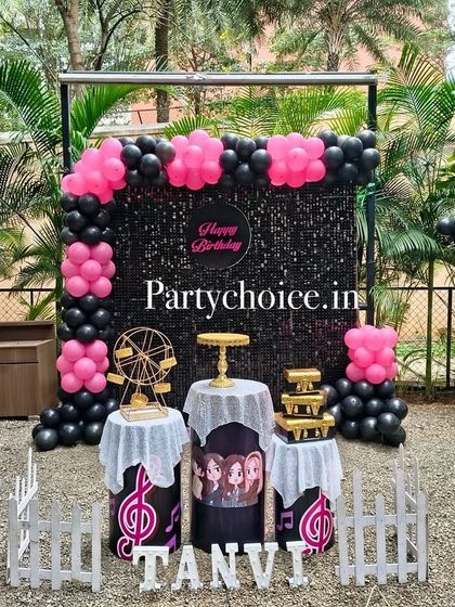 A trendy black and pink themed party. This outdoor setup includes a black sequin backdrop, black and pink balloon columns, and music-themed props for a cool, modern vibe.
