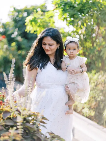 A mother and daughter walking in a garden, a lovely candid moment from a first birthday shoot.