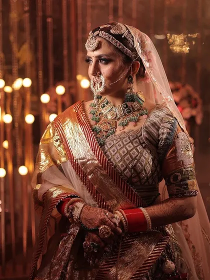A beautiful shot capturing the regal essence of a bride in a traditional saree, complemented by a heavy polki and emerald necklace set.