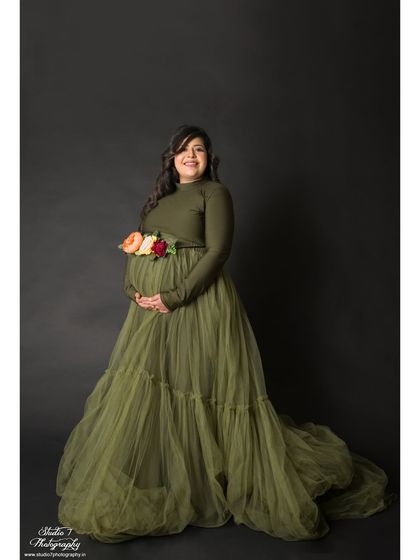 This elegant studio portrait features a beautiful olive green tulle gown. The floral belt adds a delicate touch of color and detail to the simple, classic setup.