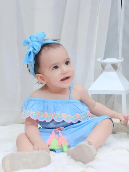 A beautiful baby girl in a blue outfit, looking up with curiosity. We use simple, clean backdrops to keep the focus entirely on your child.