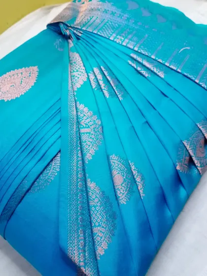 This vibrant turquoise silk saree features beautiful silver motifs. With pre-pleating, you can be confident your saree will look this neat every time you wear it.