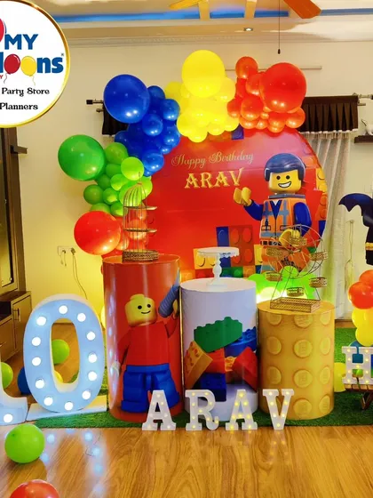 An action-packed LEGO-themed 10th birthday party. The setup includes a large '10' marquee number, LEGO character cutouts, and plinths decorated to look like giant LEGO bricks.