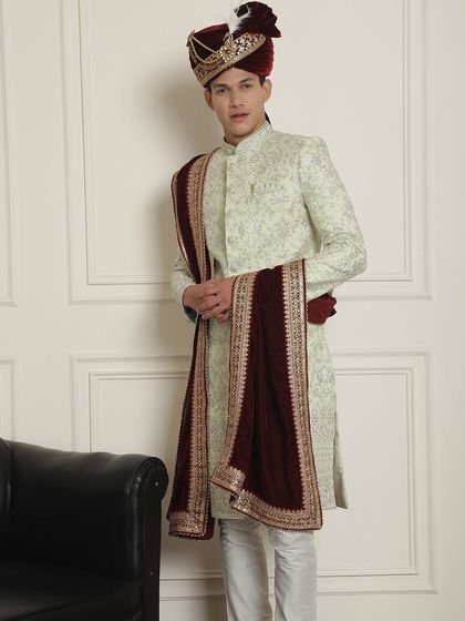 A full view of the mint green sherwani with a rich maroon velvet stole. The detailed embroidery on the stole and the matching turban complete this regal ensemble.