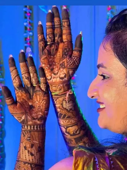 A side profile of a happy bride admiring her detailed mehendi design.