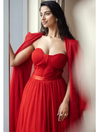 A beautiful shot of the red tulle gown styled with a matching cape. This adds an extra layer of drama and elegance to the overall look.