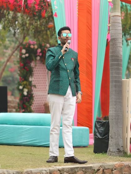 A full-length shot of me on stage at Tijara Fort Palace, addressing the guests and setting the stage for a fun-filled Mehendi.