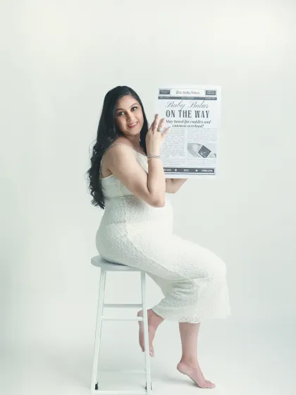 A happy solo portrait of the mom to be with her "Baby On The Way" newspaper. Her smile says it all.
