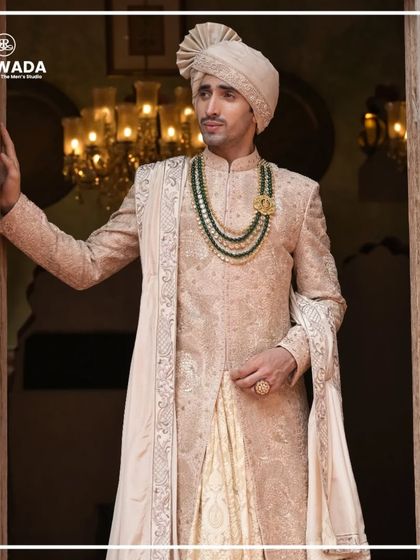 A three-quarter view of a groom in a Shauhar sherwani. The image highlights the intricate embroidery on the sleeves and the matching stole, details that define luxury.